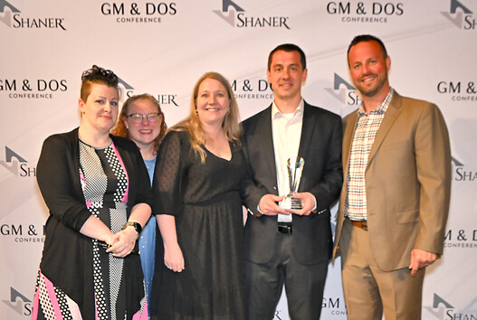 five people standing with award