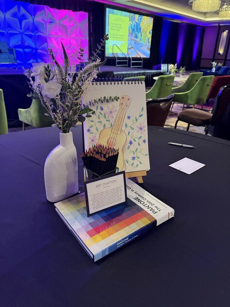 a table with a book and a drawing book and a vase of flowers