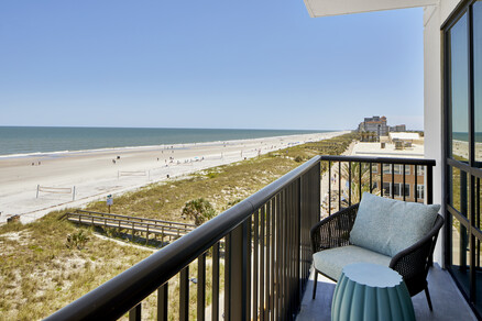 a balcony with a view of the beach and a chair