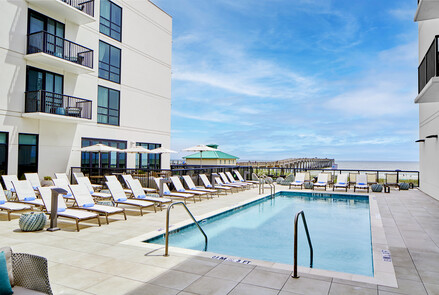 a pool with chairs and umbrellas by a building