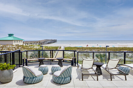 a deck with chairs and tables on a beach